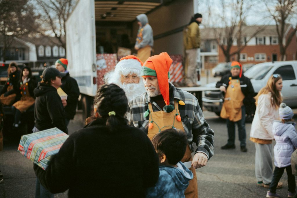 Der Weihnachtsmann und Freiwillige verteilen Geschenke von einem Lkw aus im Rahmen einer weihnachtlichen Veranstaltung für die Gemeinde.